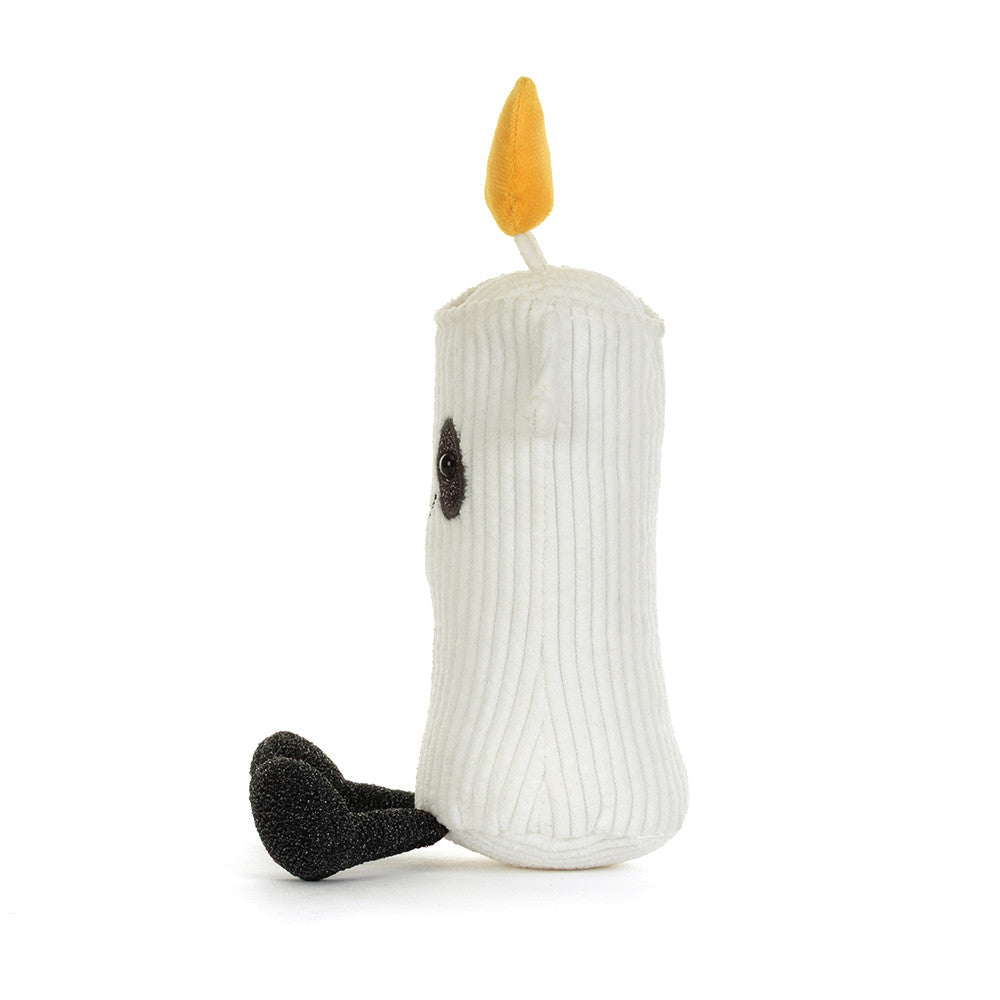 A white ribbed plush candle toy with a yellow flame on top, a small black embroidered eye, and a black textured foot, photographed on a clean white background.