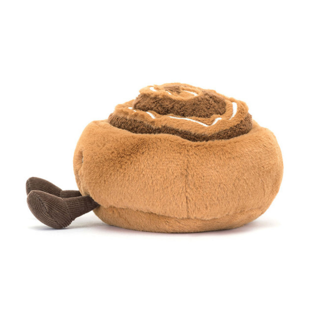 The side of a brown plush toy resembling a cinnamon bun with a happy facial expression, made from brown fur-like material with a cream-colored icing on top.
