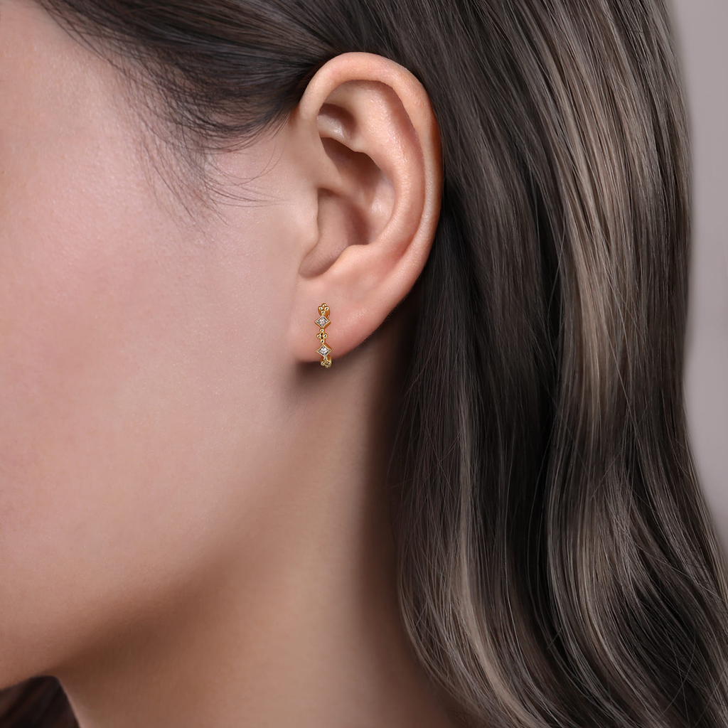 Close-up of an ear wearing a gold earring with a blurred background