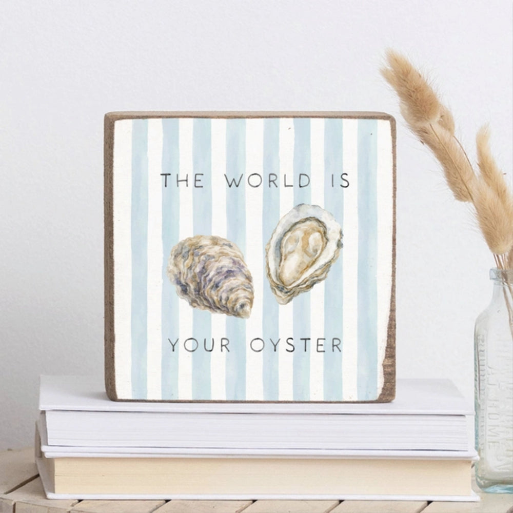 Decorative sign with oyster illustration and 'The world is your oyster' text on a striped background, placed on books.