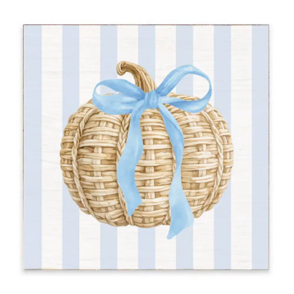 A decorative plaque with a woven pumpkin and a blue bow tie on it displayed on a white background.