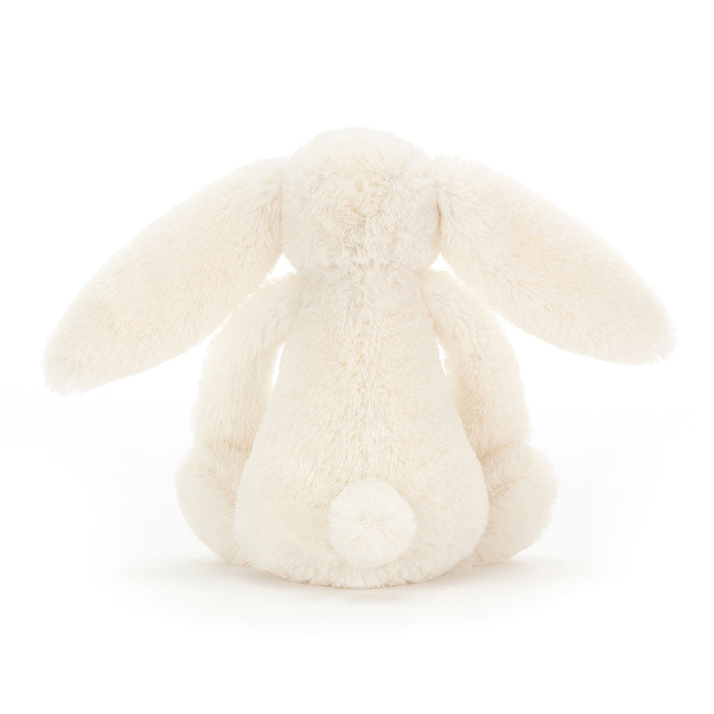 A side photo of the back of the little sized cream-colored plush bunny toy on a white background.