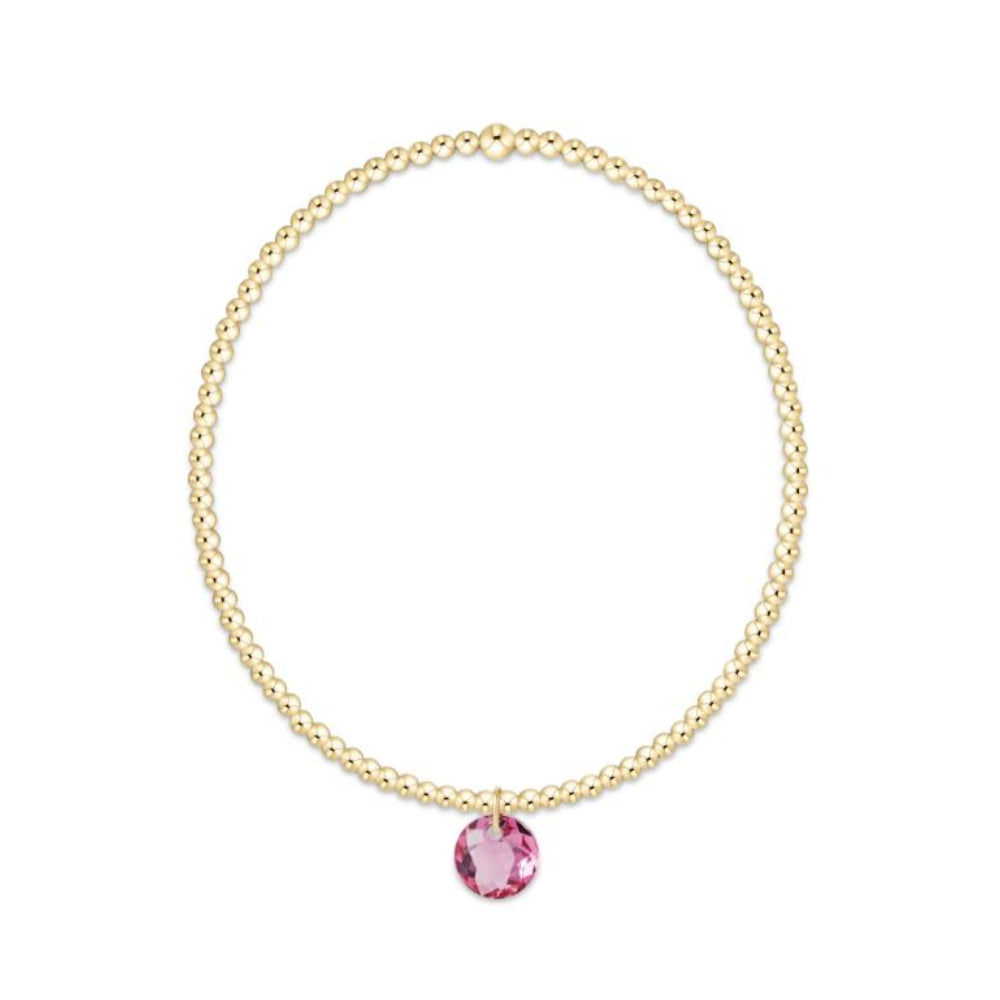 Gold bracelet with a pink gemstone on a white background