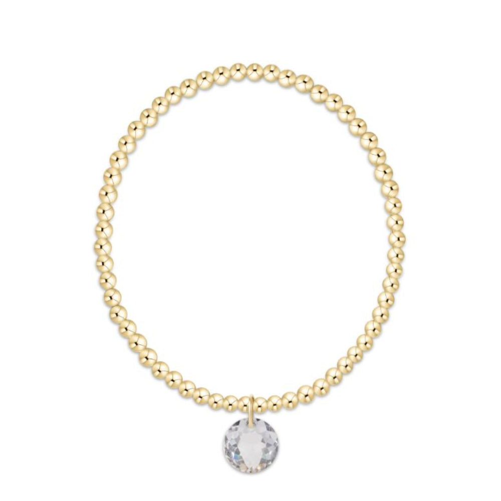 Gold beaded bracelet with a clear crystal charm on a white background