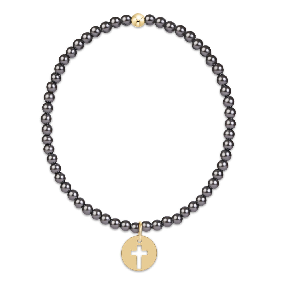 A beaded bracelet featuring small, dark gray round beads and a gold-toned circular pendant with a white cross, displayed on a clean white background.