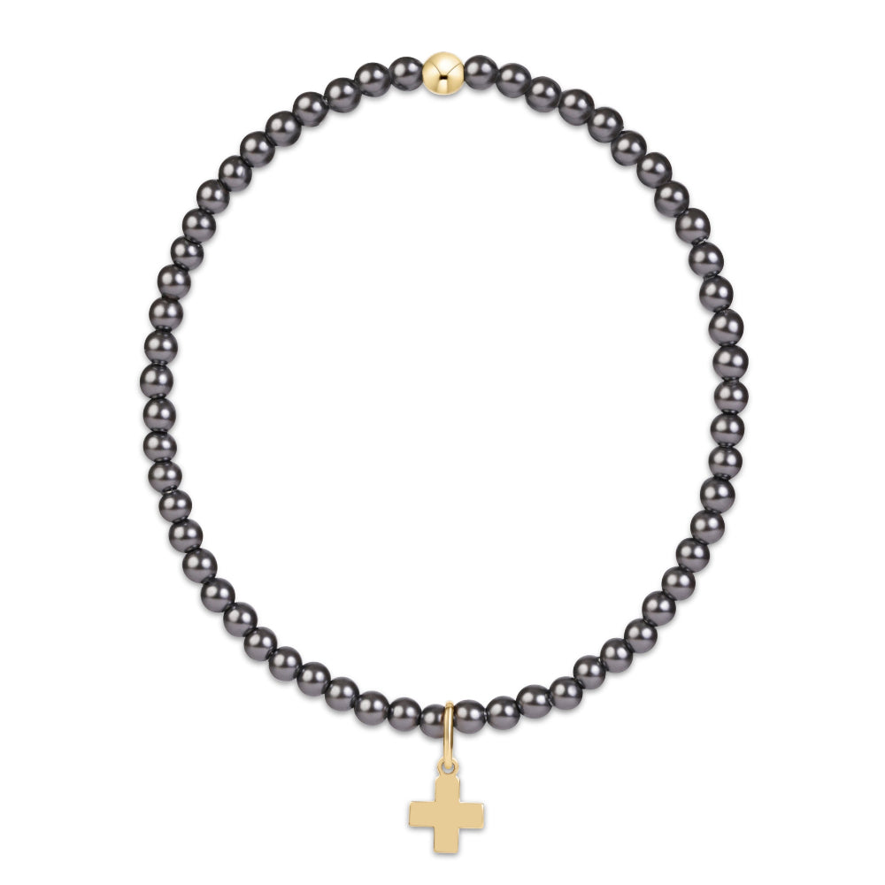 A beaded bracelet featuring small, dark gray to black round pearls with a small gold cross charm displayed on a clean white background.