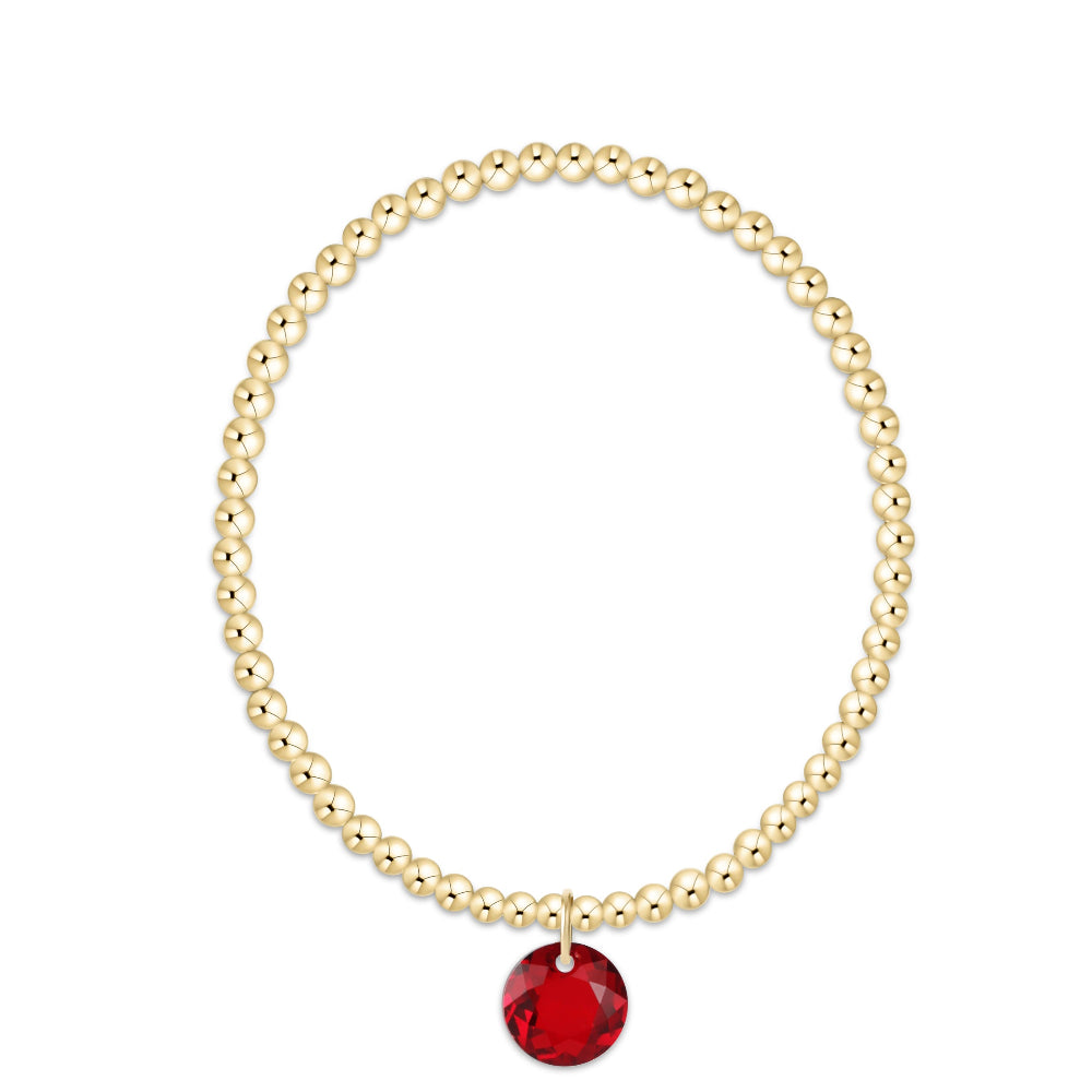 A gold beaded bracelet with a faceted red round crystal pendant, displayed on a clean white background.
