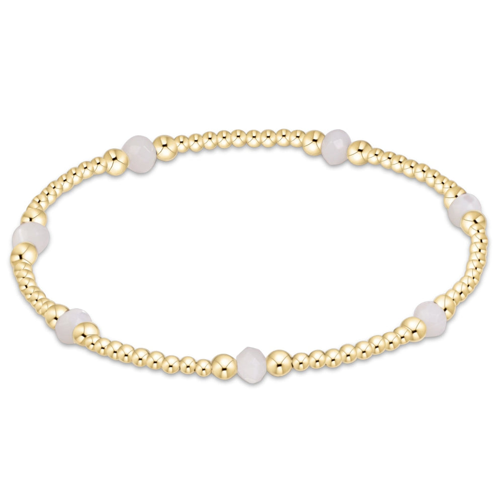 A delicate gold beaded stretch bracelet featuring alternating smooth white oval beads and polished round gold beads, displayed on a clean white background.