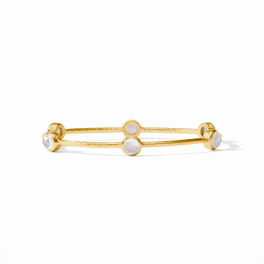 A delicate gold bangle bracelet featuring round bezel-set white stones, photographed on a clean white background with a soft shadow.
