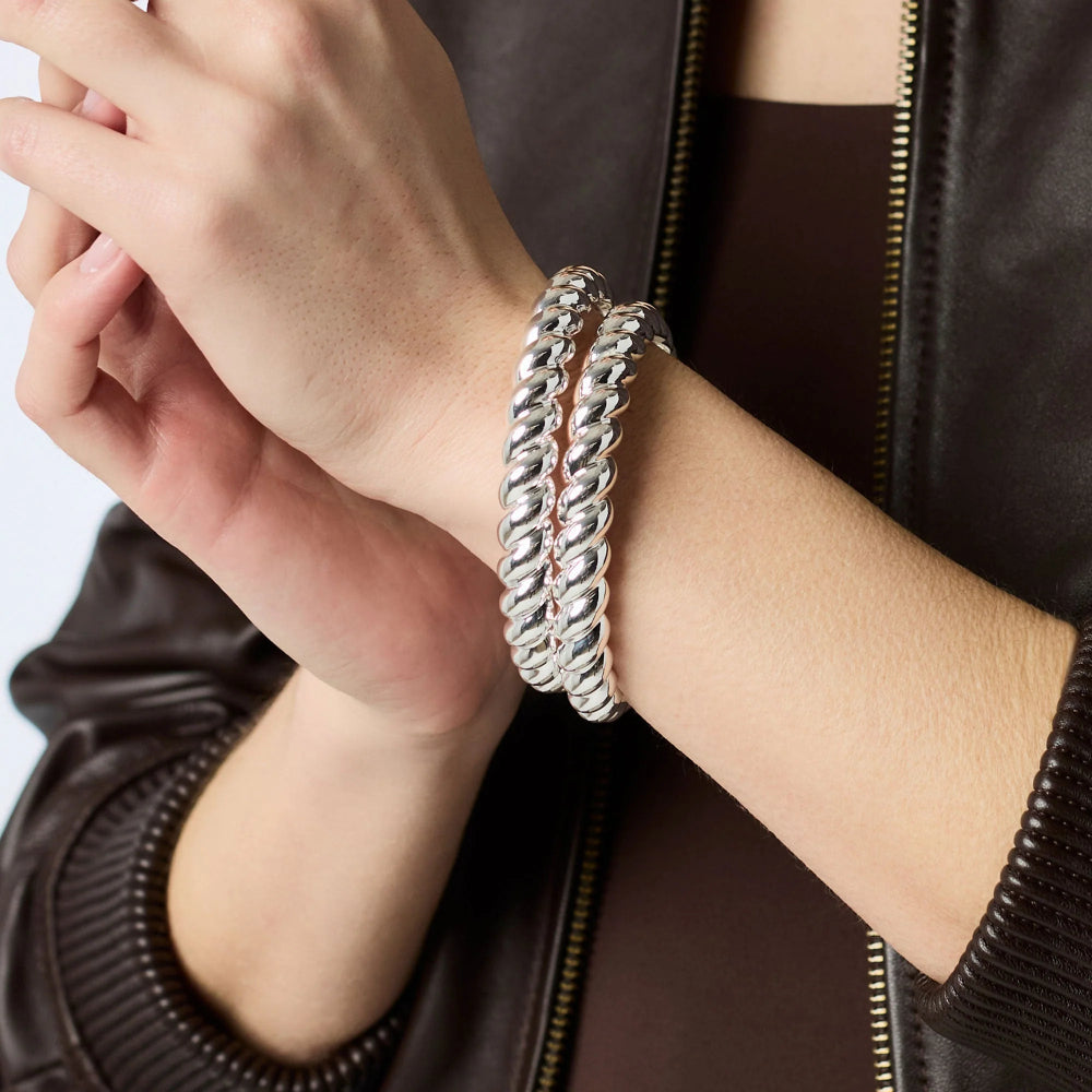Close-up of a person's wrist wearing a silver bracelet with a dark jacket background