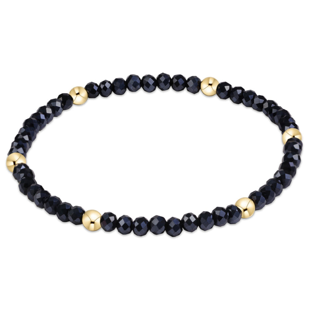 A beaded stretch bracelet featuring faceted navy beads and small metallic gold accent beads, displayed on a clean white background.