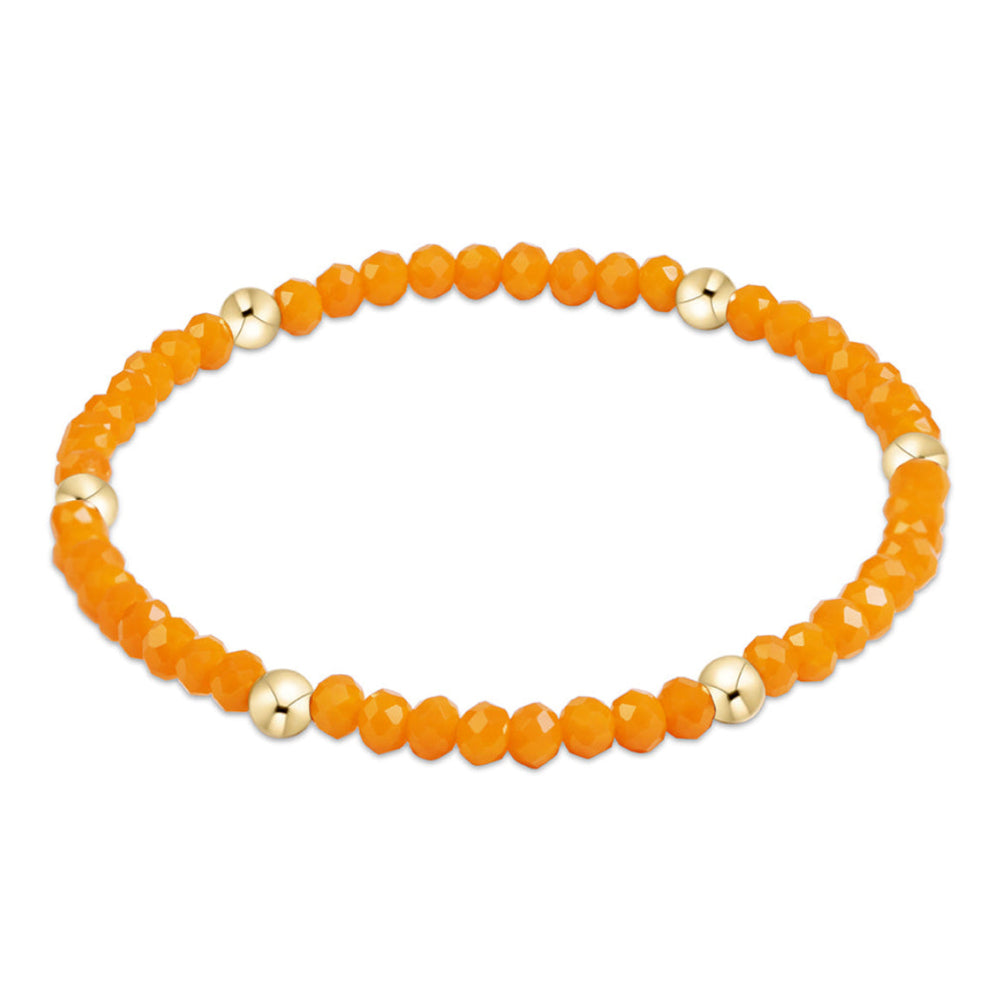 An orange beaded stretch bracelet with alternating faceted orange beads and polished gold spacer beads, shown on a plain white background.