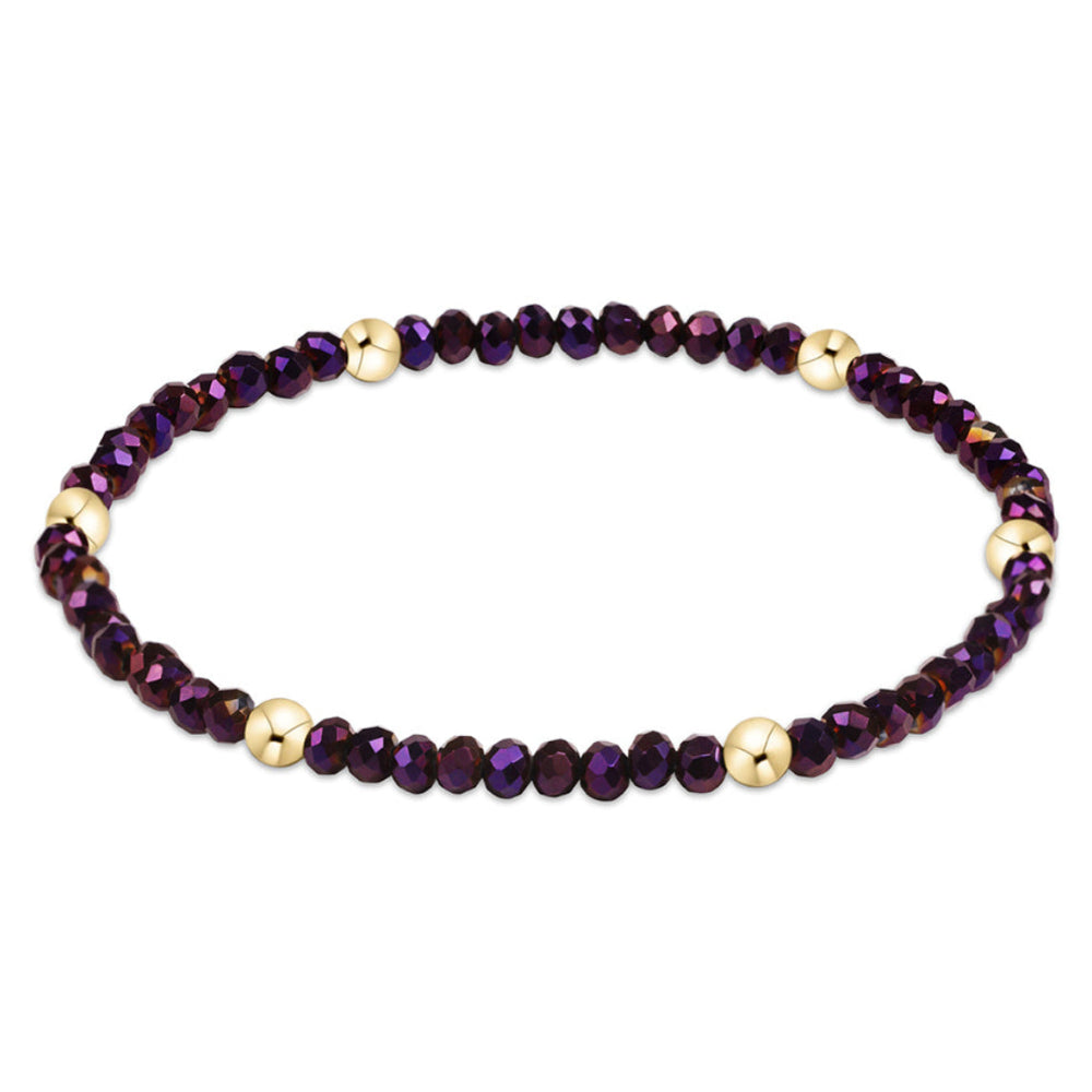 A beaded stretch bracelet featuring faceted dark purple beads and alternating polished gold spacer beads, displayed on a clean white background.