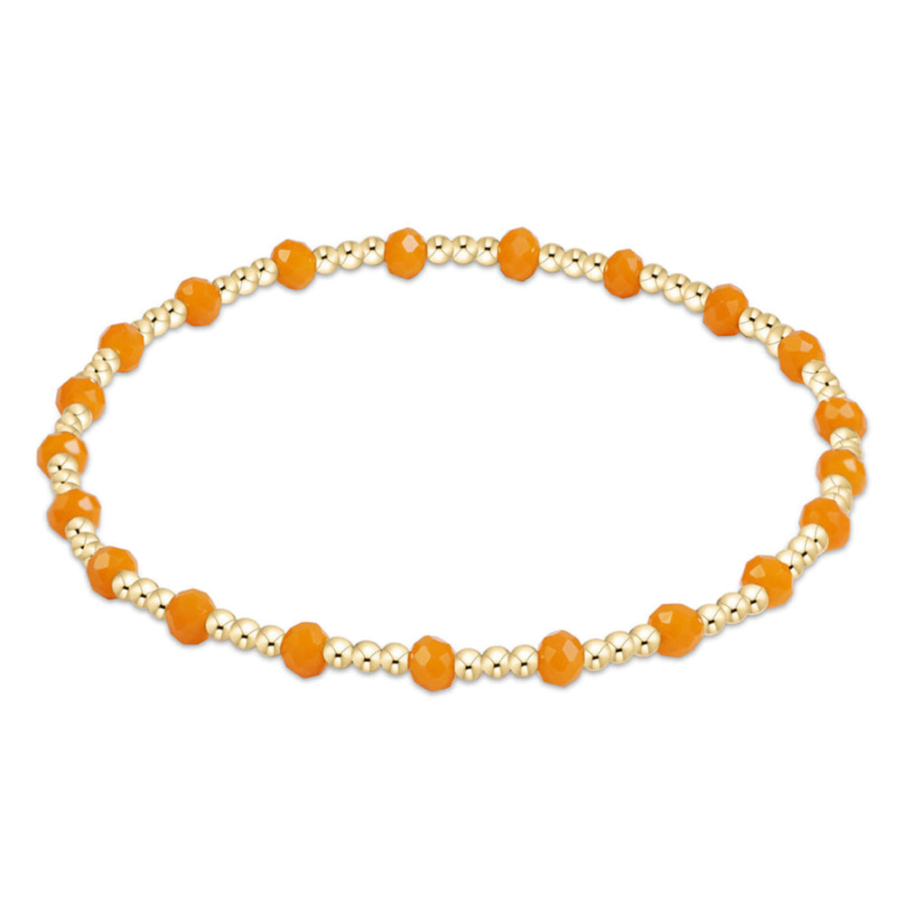 A beaded stretch bracelet featuring faceted orange beads alternating with small metallic gold seed beads, displayed on a clean white background.