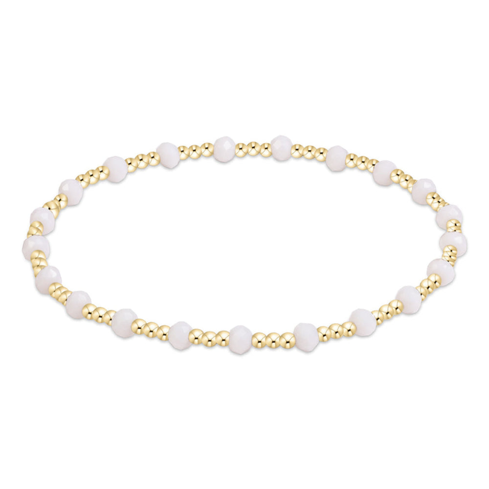 A delicate beaded bracelet featuring alternating white round beads and small metallic gold seed beads, displayed on a clean white background.