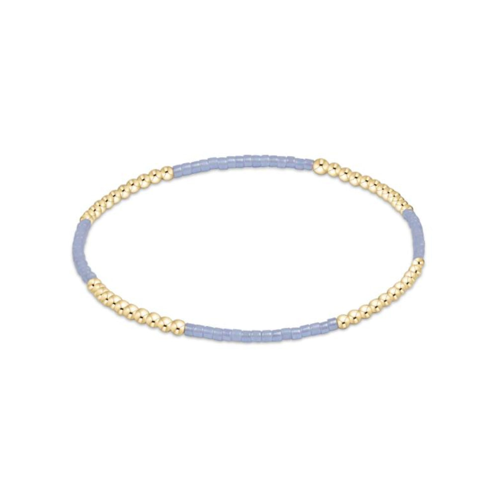Two-toned gold and light blue bracelet on a white background