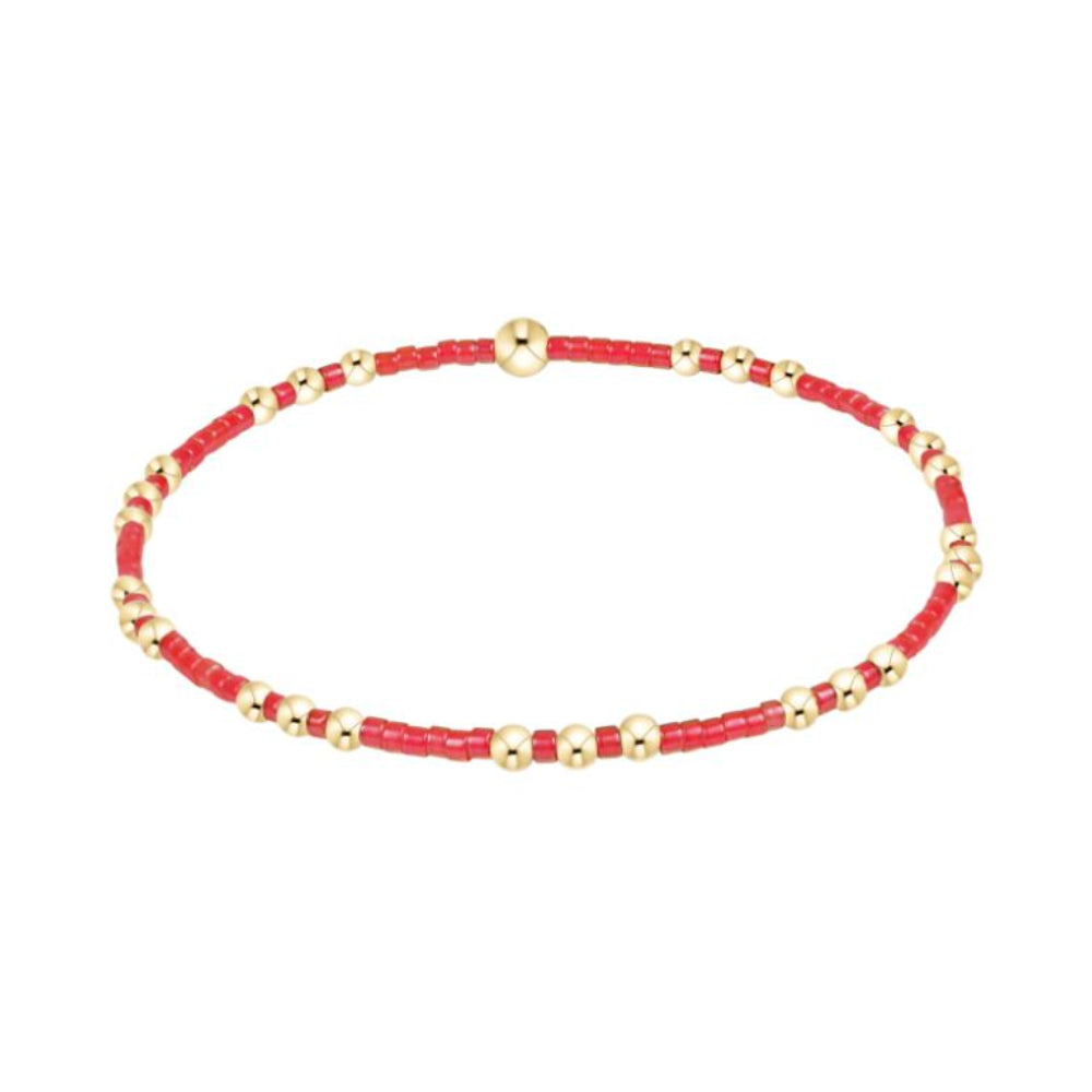 Red beaded bracelet with gold accents on a white background