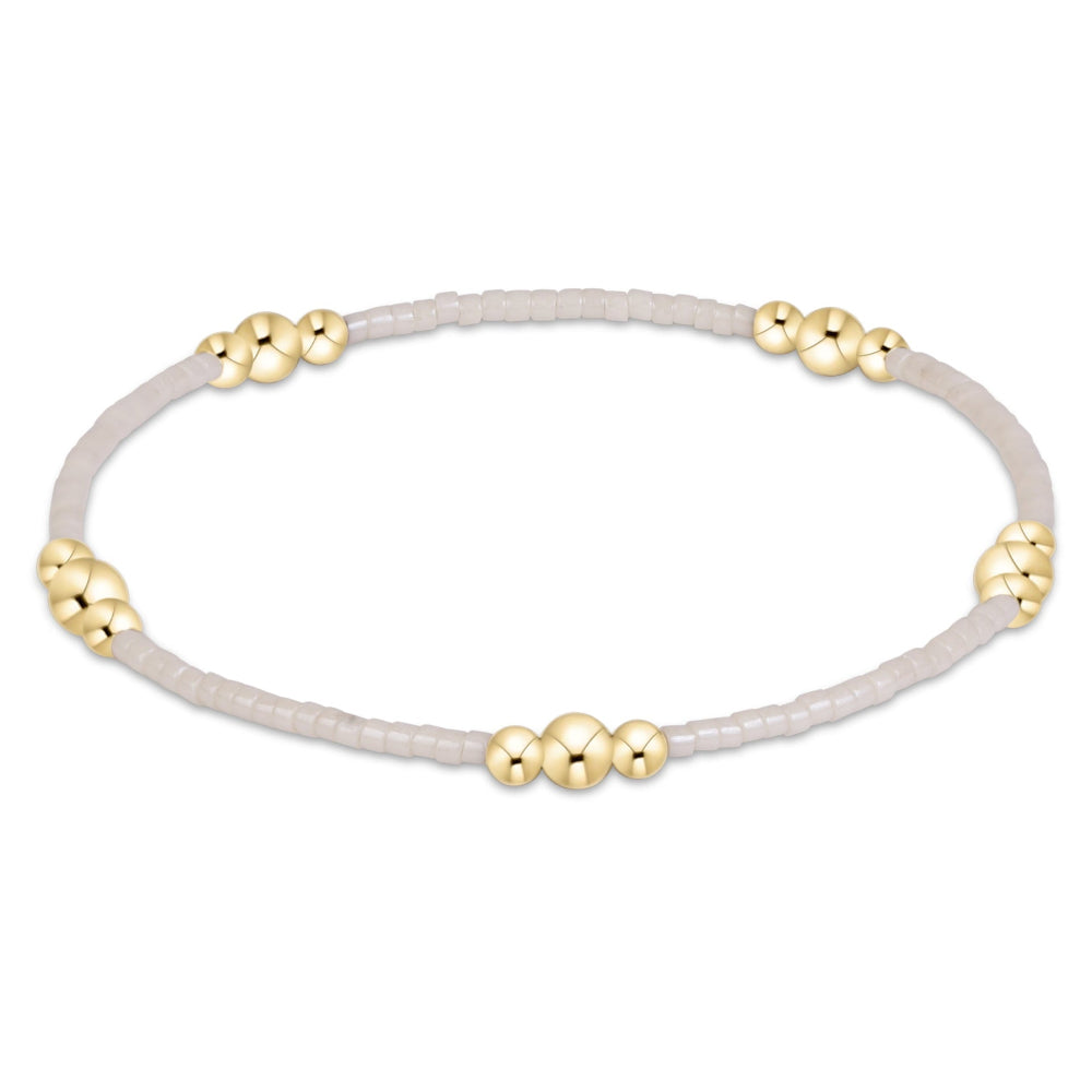A delicate beaded bracelet with a light gray translucent cord and small gold metallic bead accents, shown against a plain white background.