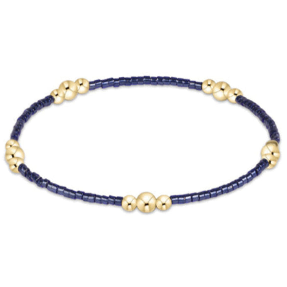 A delicate beaded bracelet with a dark navy blue bead strand and small gold-toned decorative beads spaced along the band, shown on a plain white background.