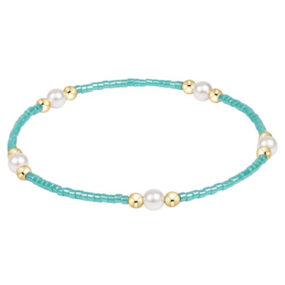 Turquoise beaded bracelet with pearls and gold accents on a white background