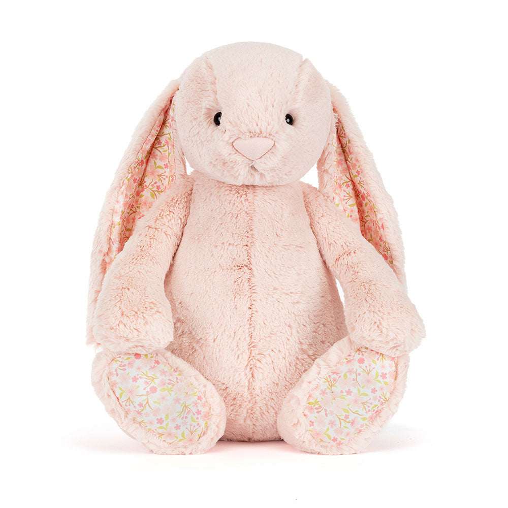A photo of the front of a big sized pink plush bunny with floral-patterned ears on a white background.