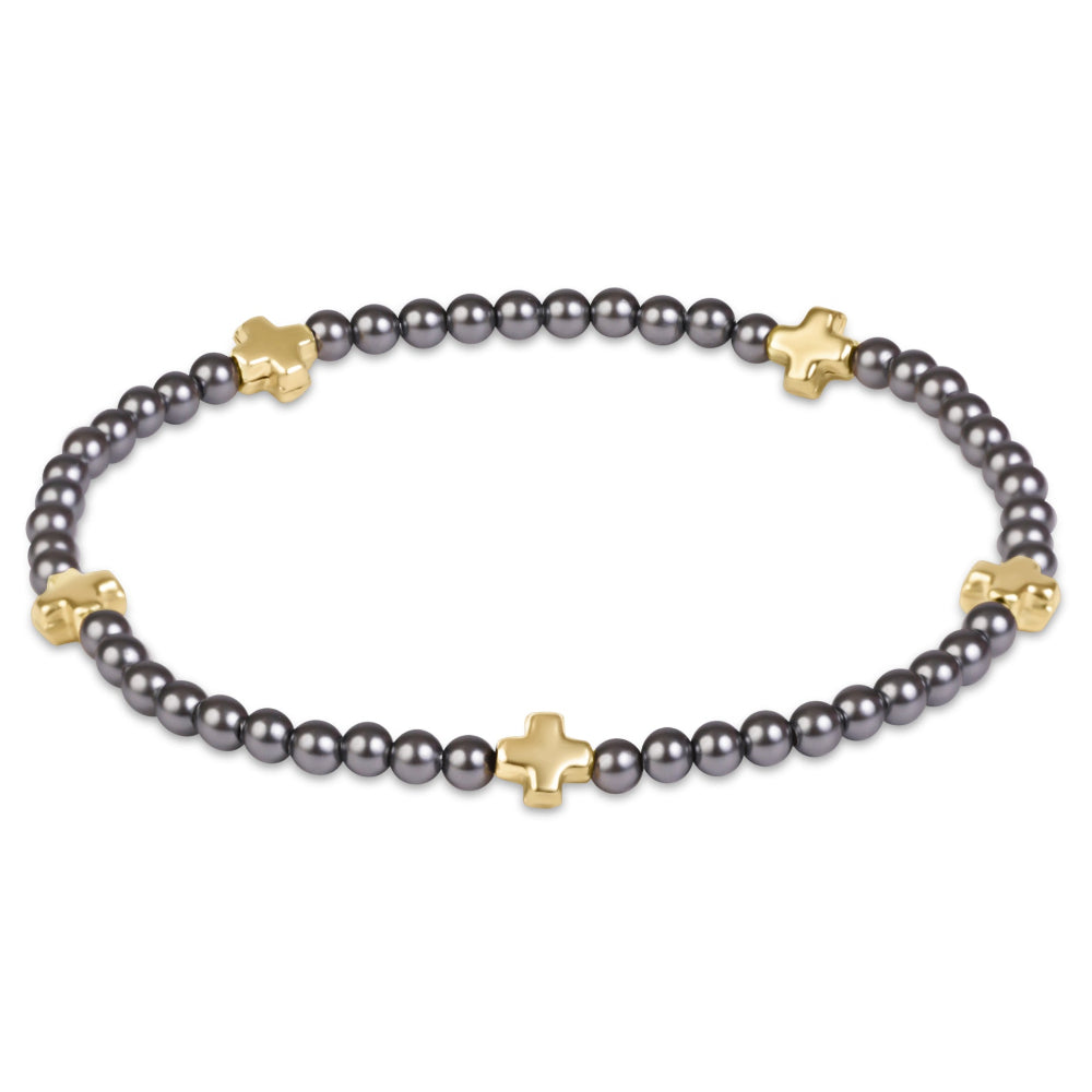 A beaded stretch bracelet featuring dark gray pearls and small gold cross-shaped charms, displayed on a clean white background.