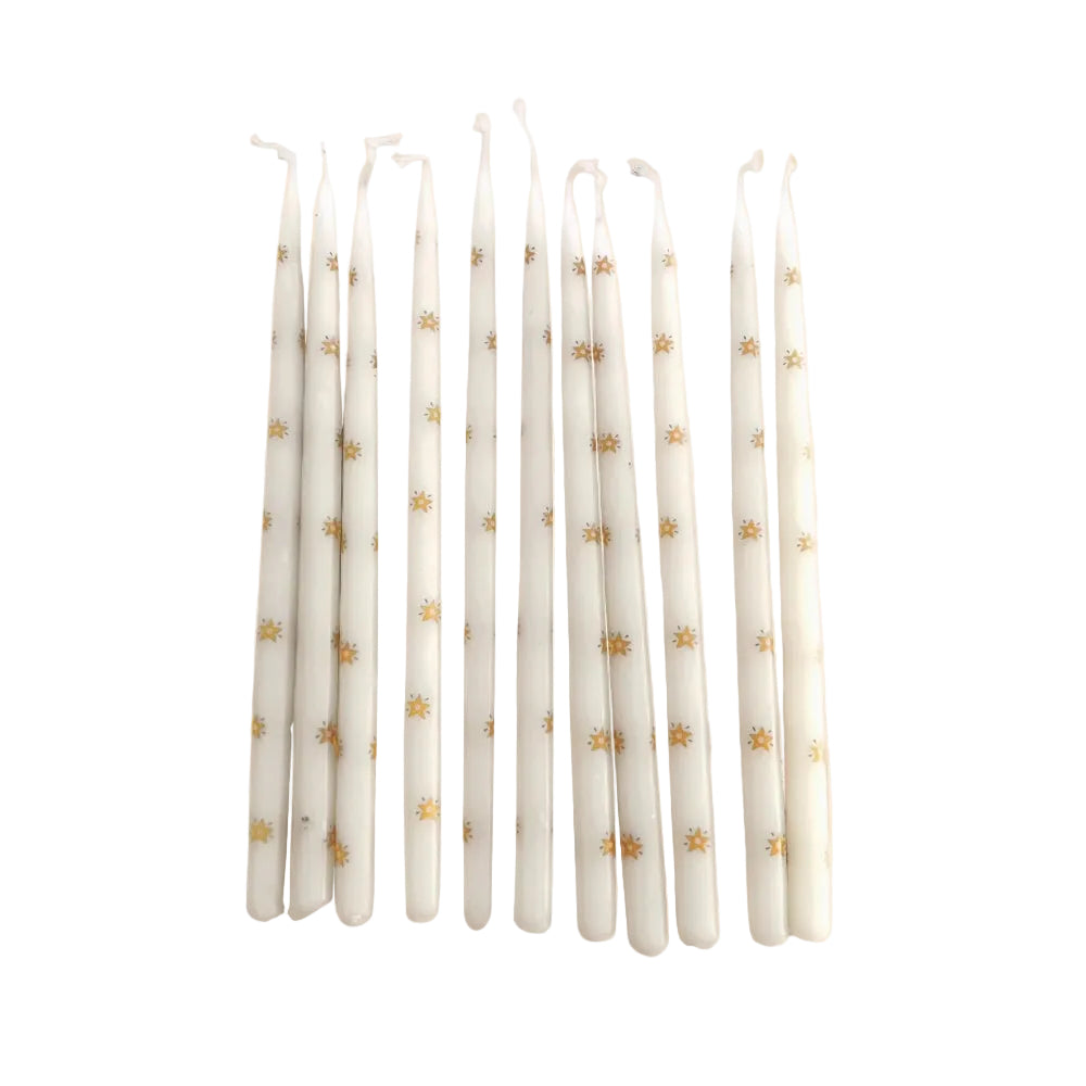 Ten small tapered off white candles with gold star details throughout on a white background.