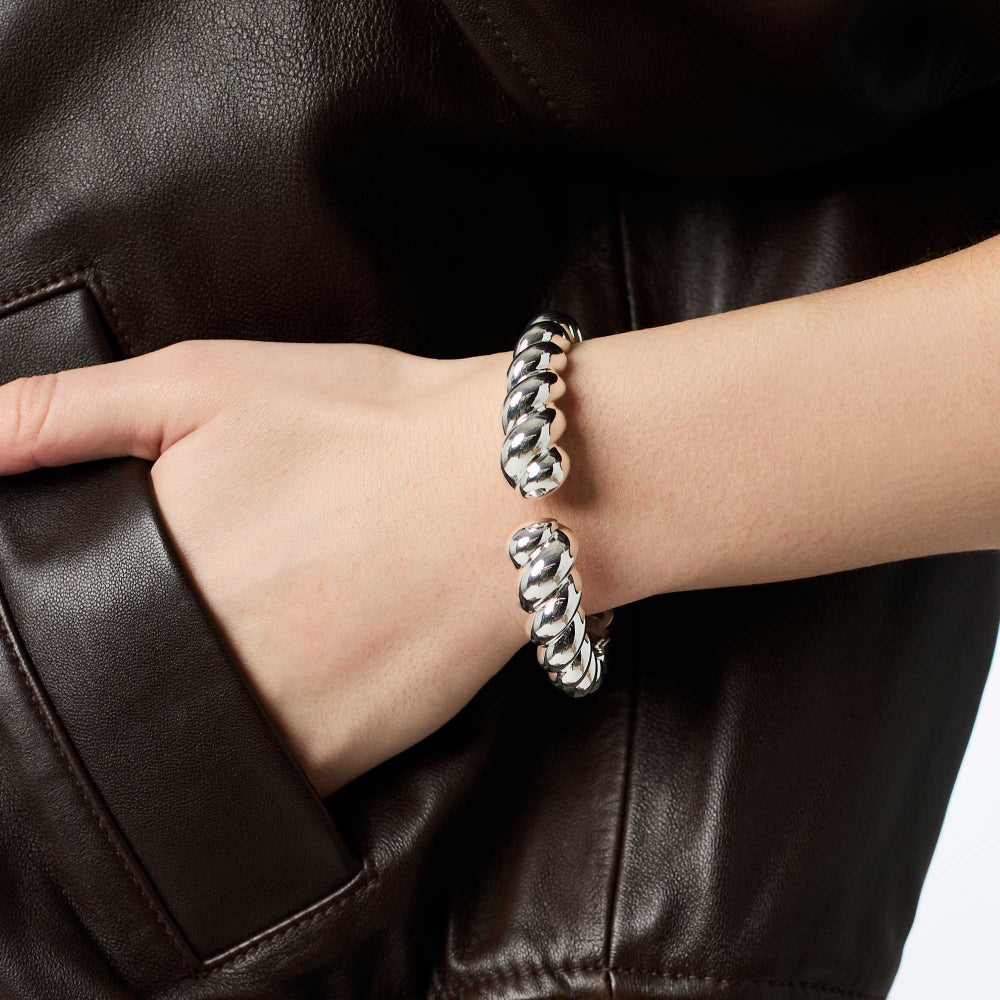 Silver braided bracelet on a wrist against a dark leather background