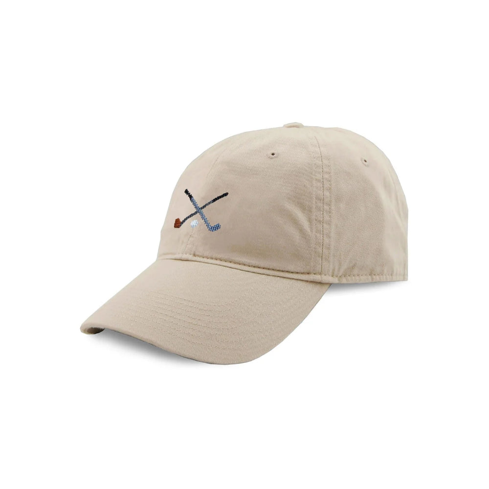 A beige baseball cap featuring an embroidered crossed polo mallet and club design on the front, set against a plain white background.