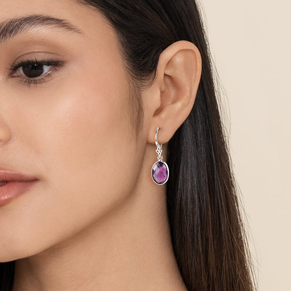 Close-up of a woman wearing a silver & amethyst drop earring