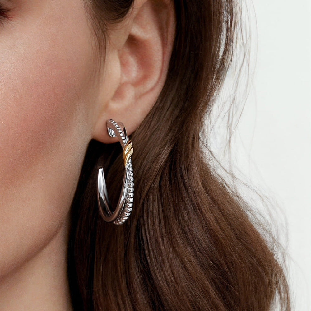 Close-up of a person wearing a silver & gold hoop earring