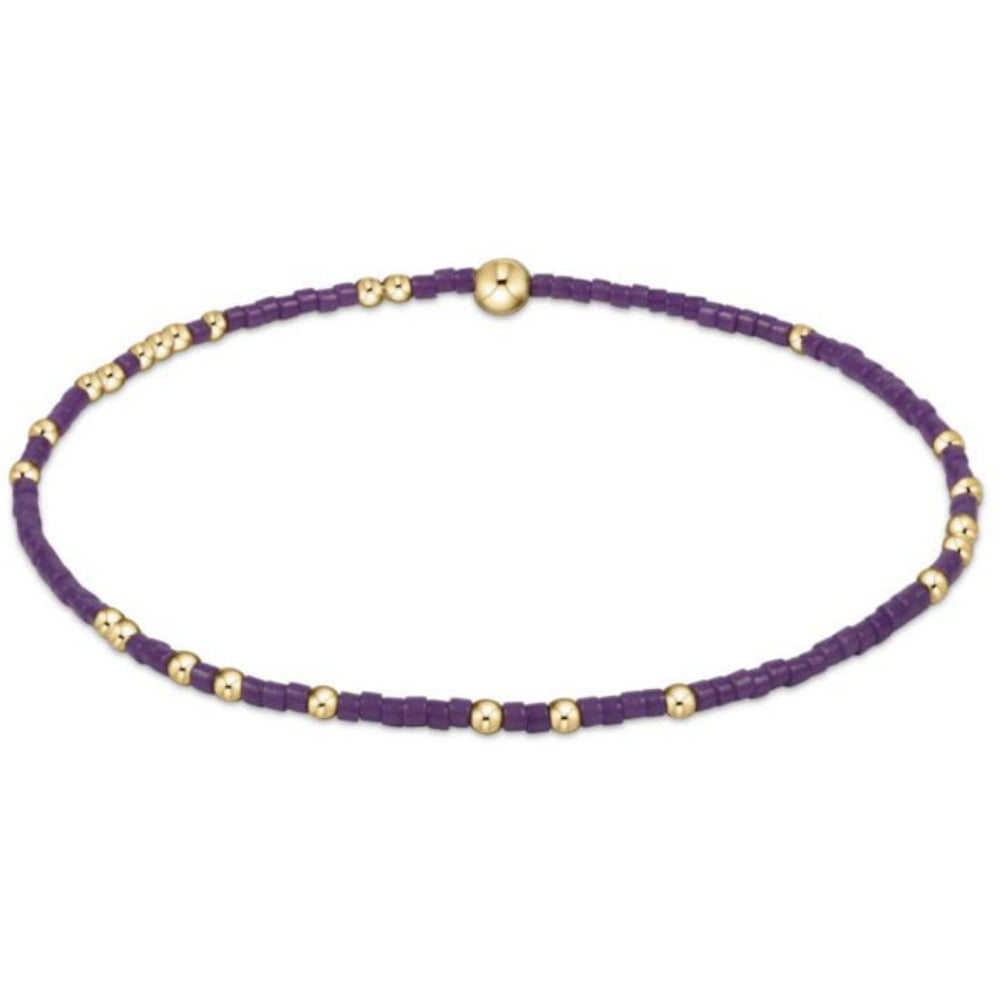 Purple beaded bracelet with gold beads on a white background