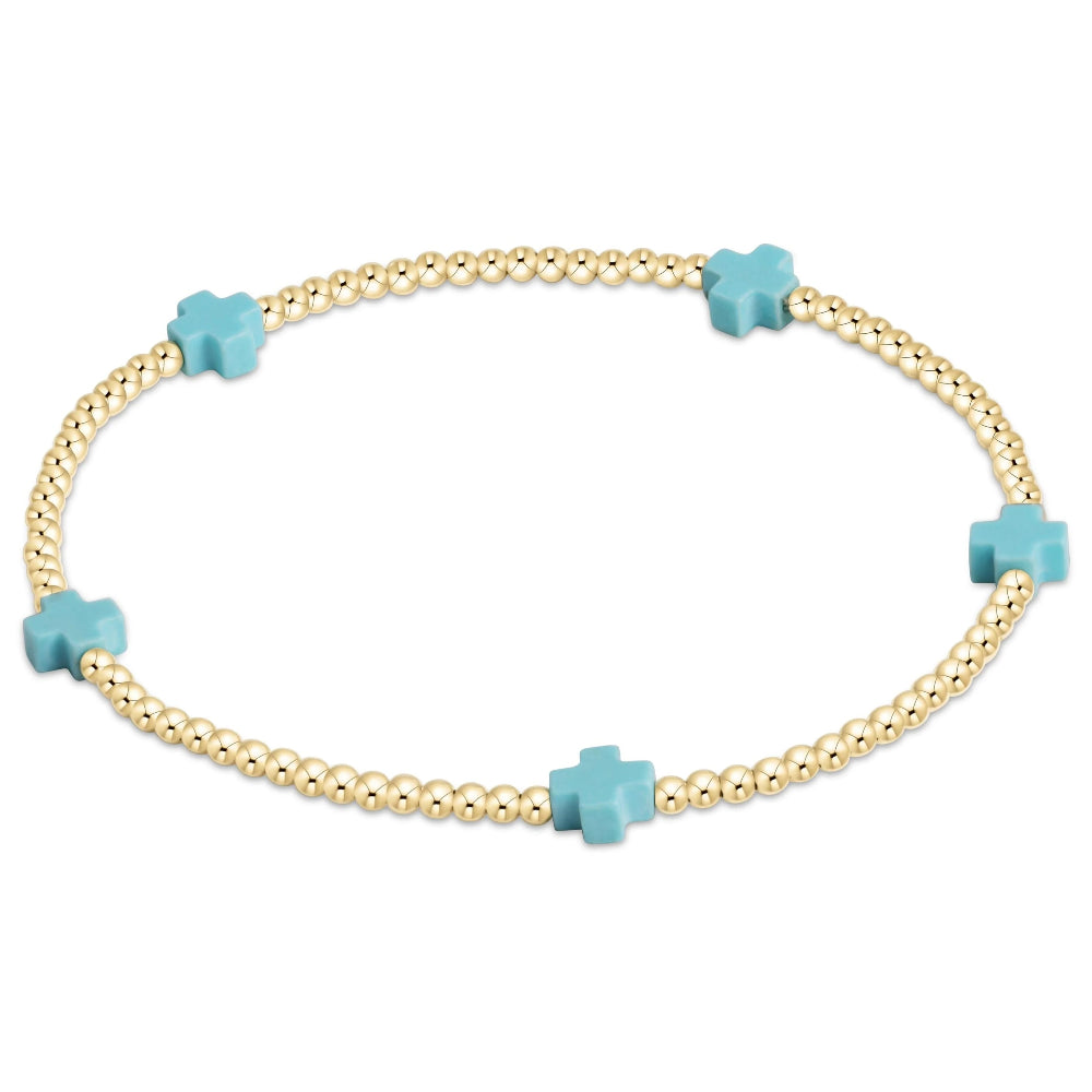 Gold bracelet with 5 turquoise cross shaped beads on a white background