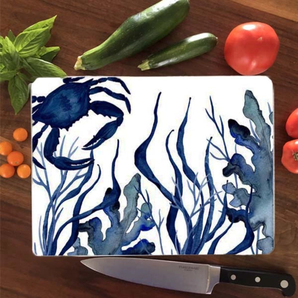 Chopping board with blue crab and seaweed design on a wooden surface with vegetables and a knife.