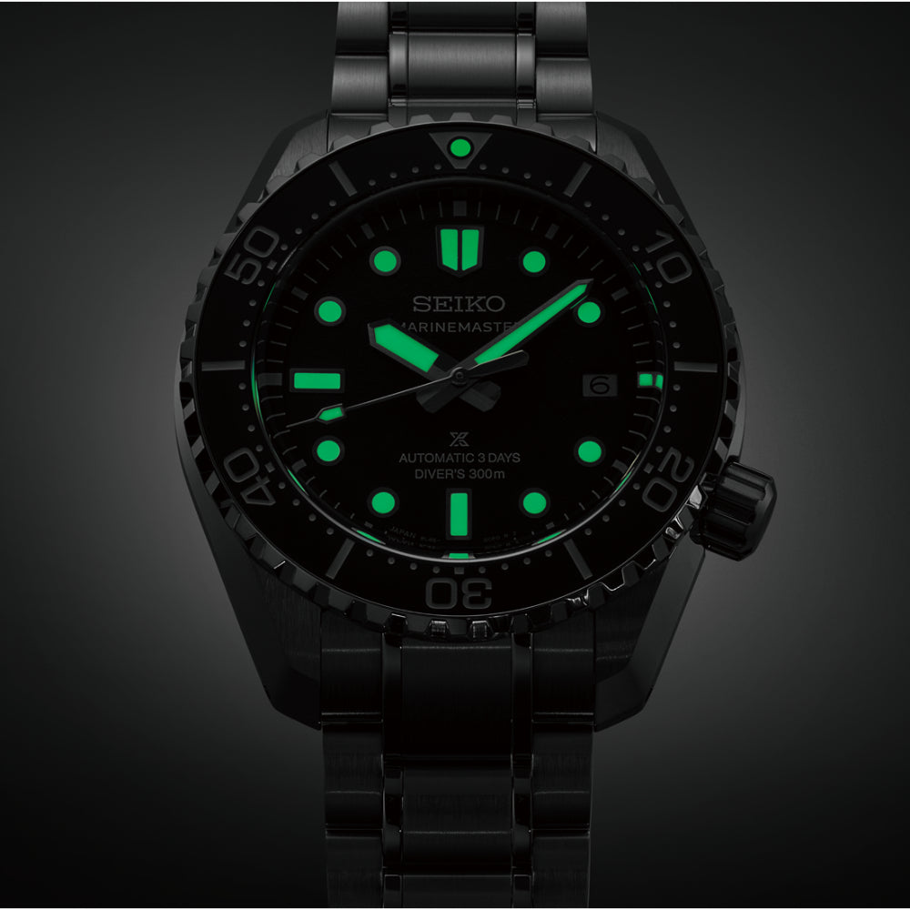 A Seiko dive watch with a black stainless steel case and integrated bracelet, featuring a black dial with bright green luminescent hour markers, hands, and bezel details, shown against a dark background.