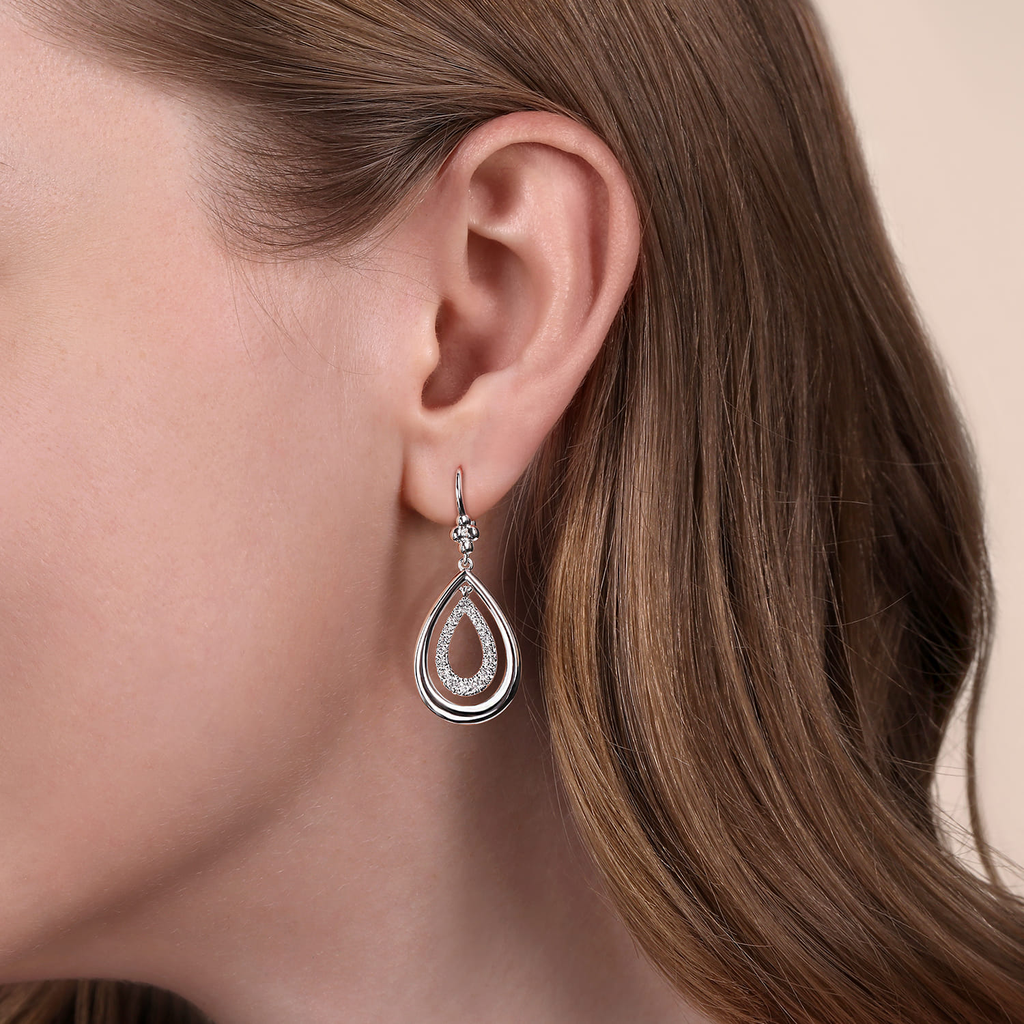 Teardrop-shaped earrings worn by a person with brown hair.