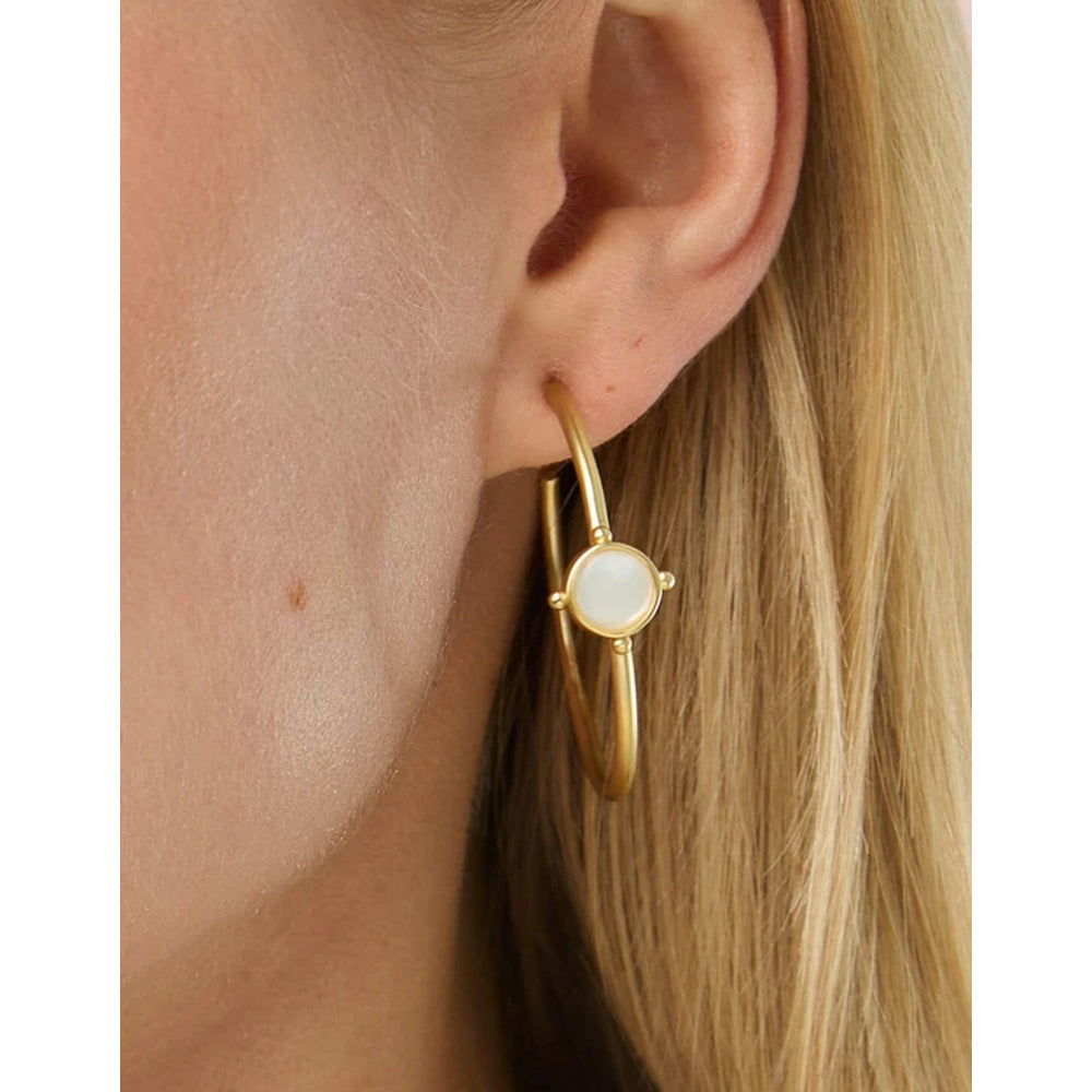 Close up of a blonde woman's ear wearing a gold hoop with mother-of-pearl detail.