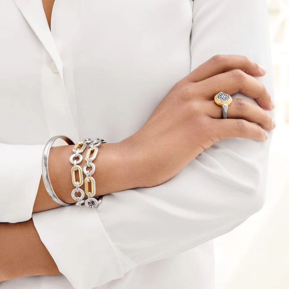 Woman's arm wearing silver bracelets and a ring on a white background.