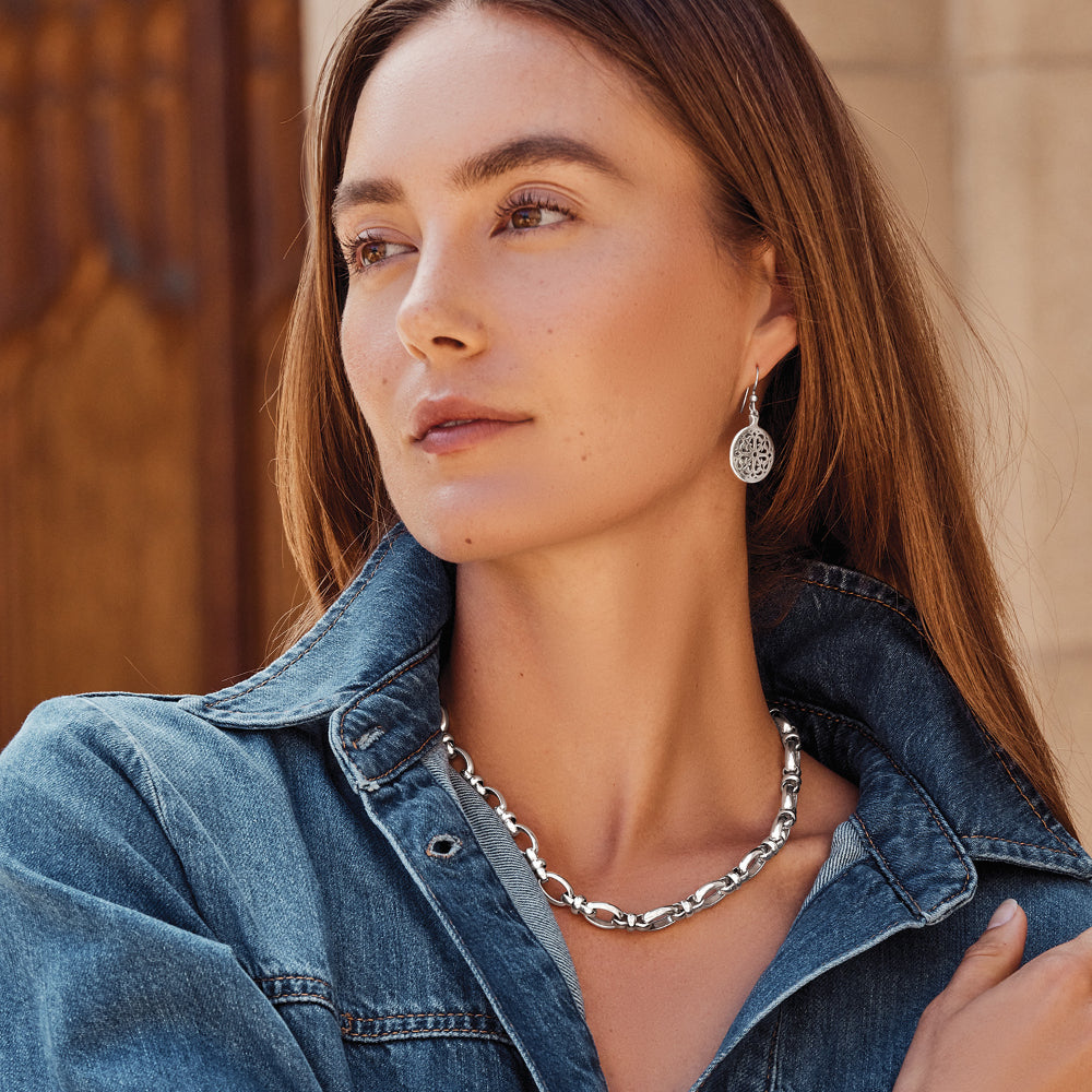 Woman wearing a denim jacket and silver necklace with a blurred background