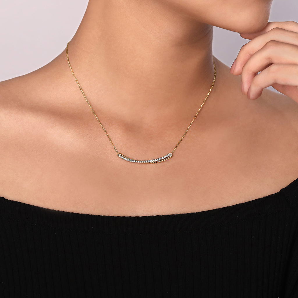 model wearing gold and silver bar necklace pendant with clear stones on natural background