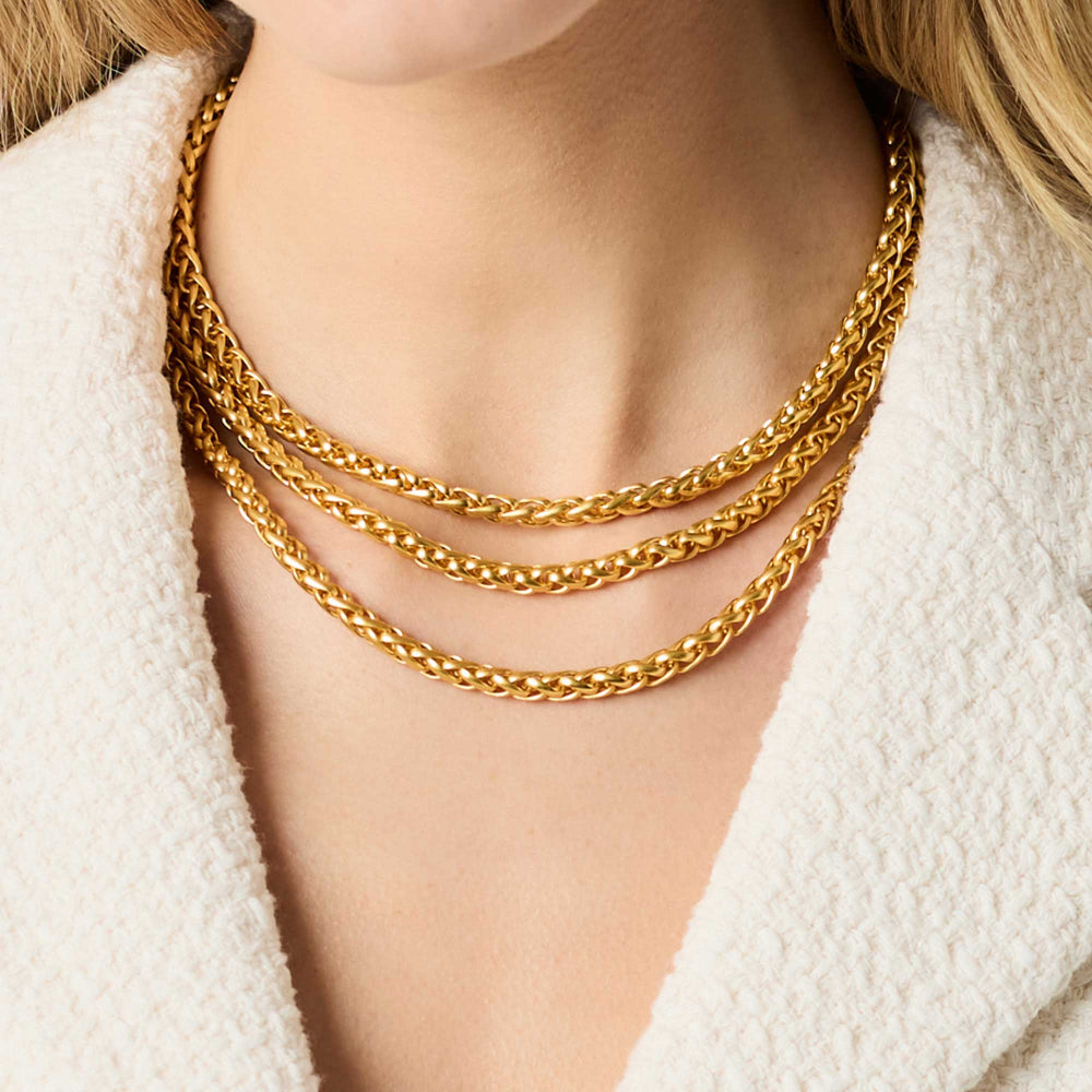 Gold chain necklace on a person wearing a white textured garment