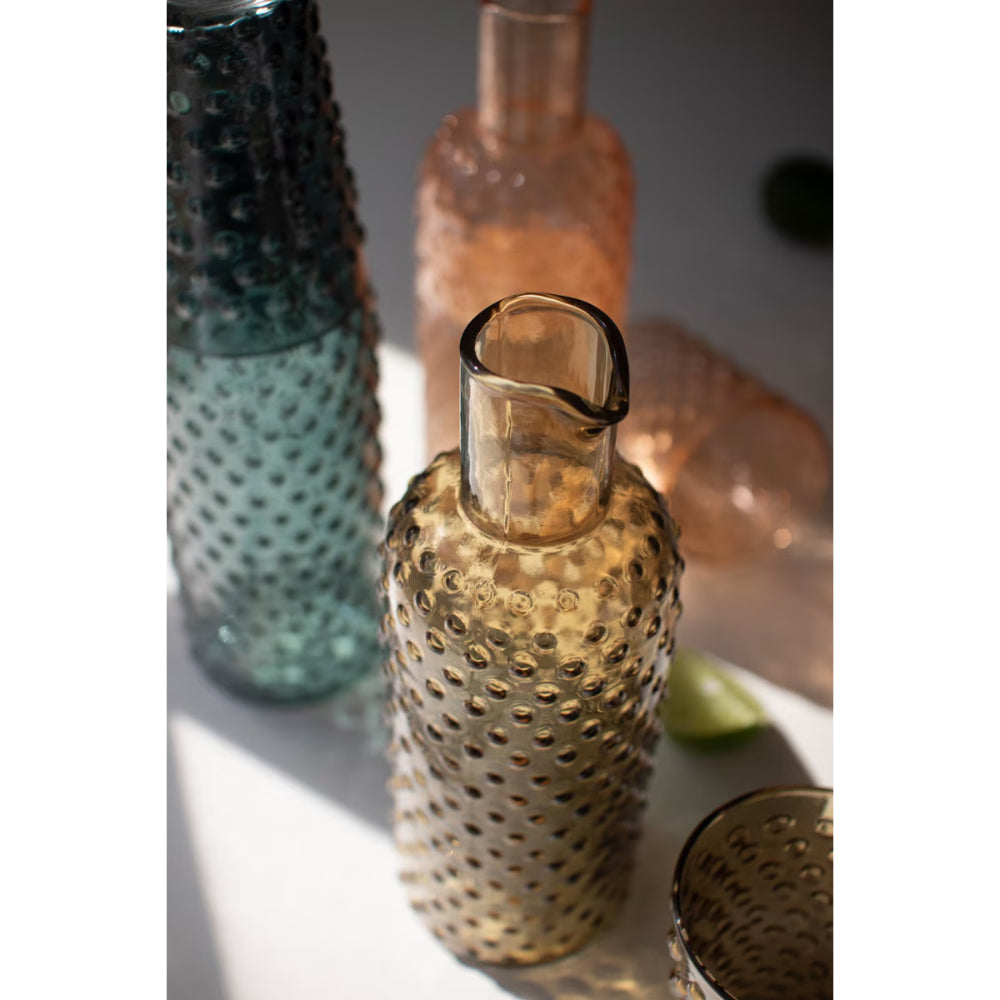 Decorative glass bottles with textured surfaces on a white surface.
