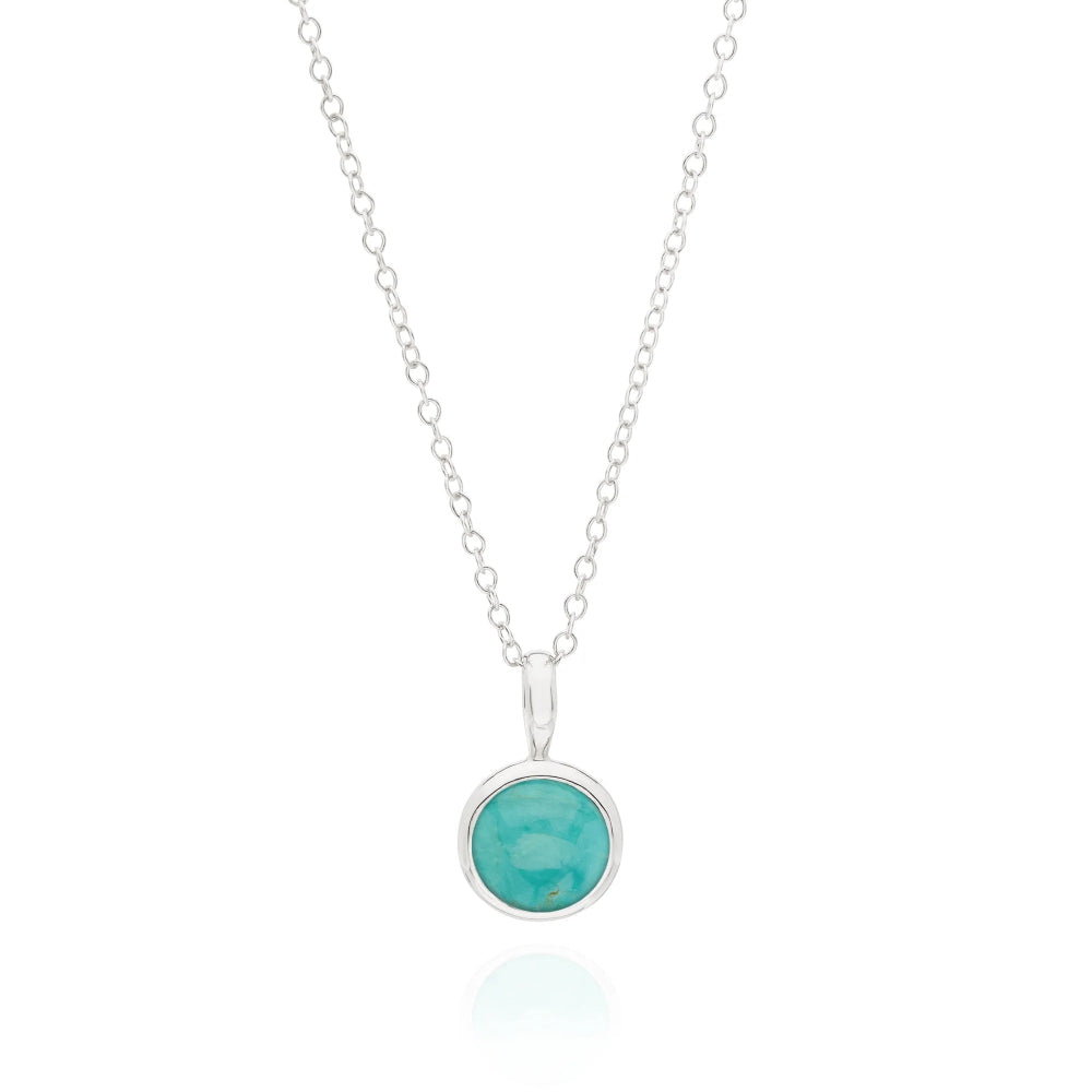 A silver chain necklace with a round bezel-set turquoise pendant