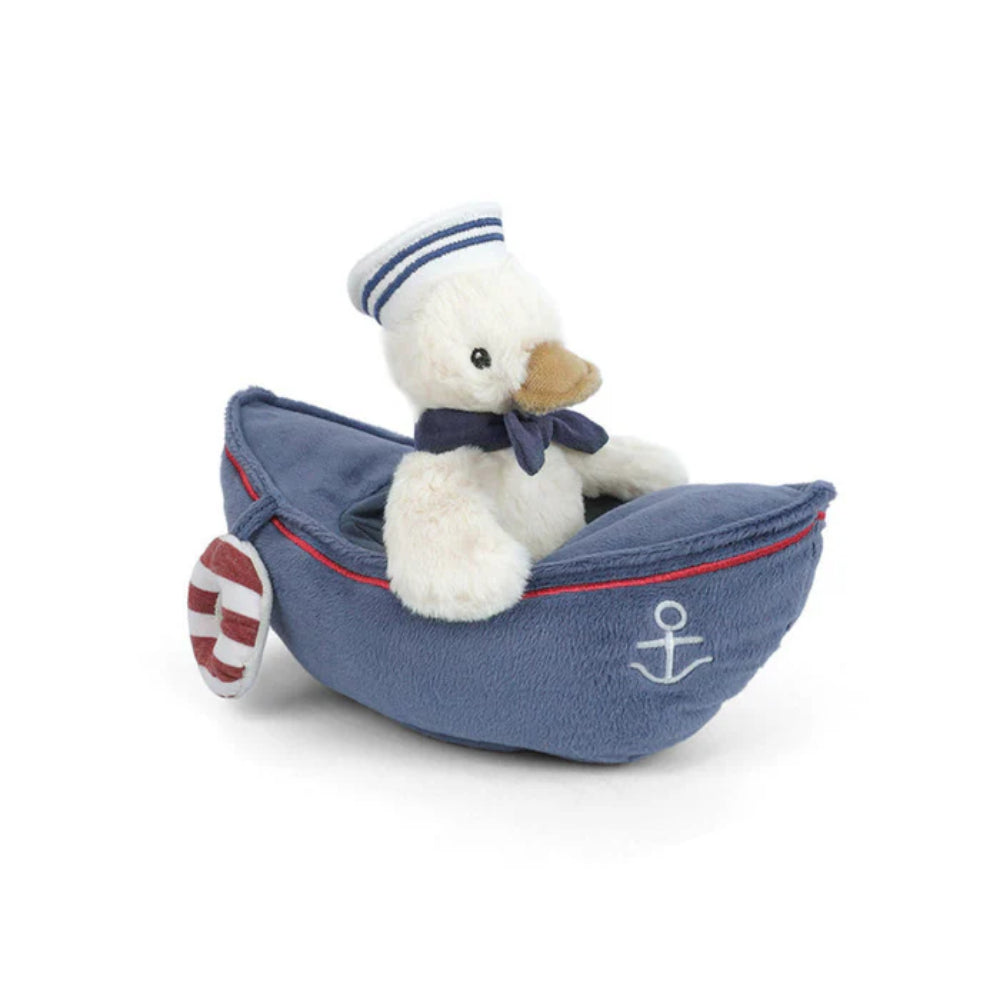 White stuffed toy duck dressed a sailor in a blue boat with an anchor on a white background.