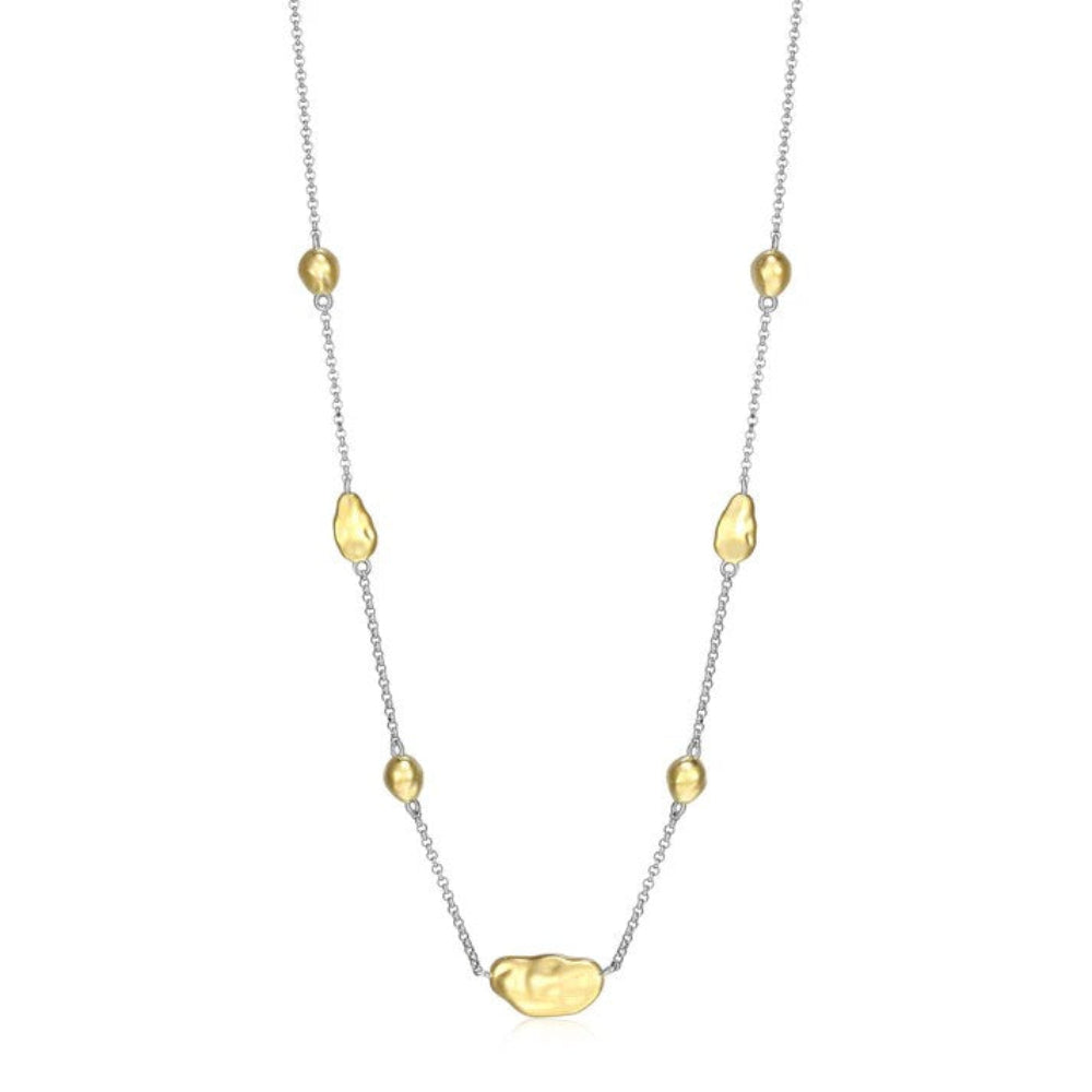 A delicate necklace featuring a fine silver chain accented with irregular, organic-shaped polished gold beads, including one larger central bead,
