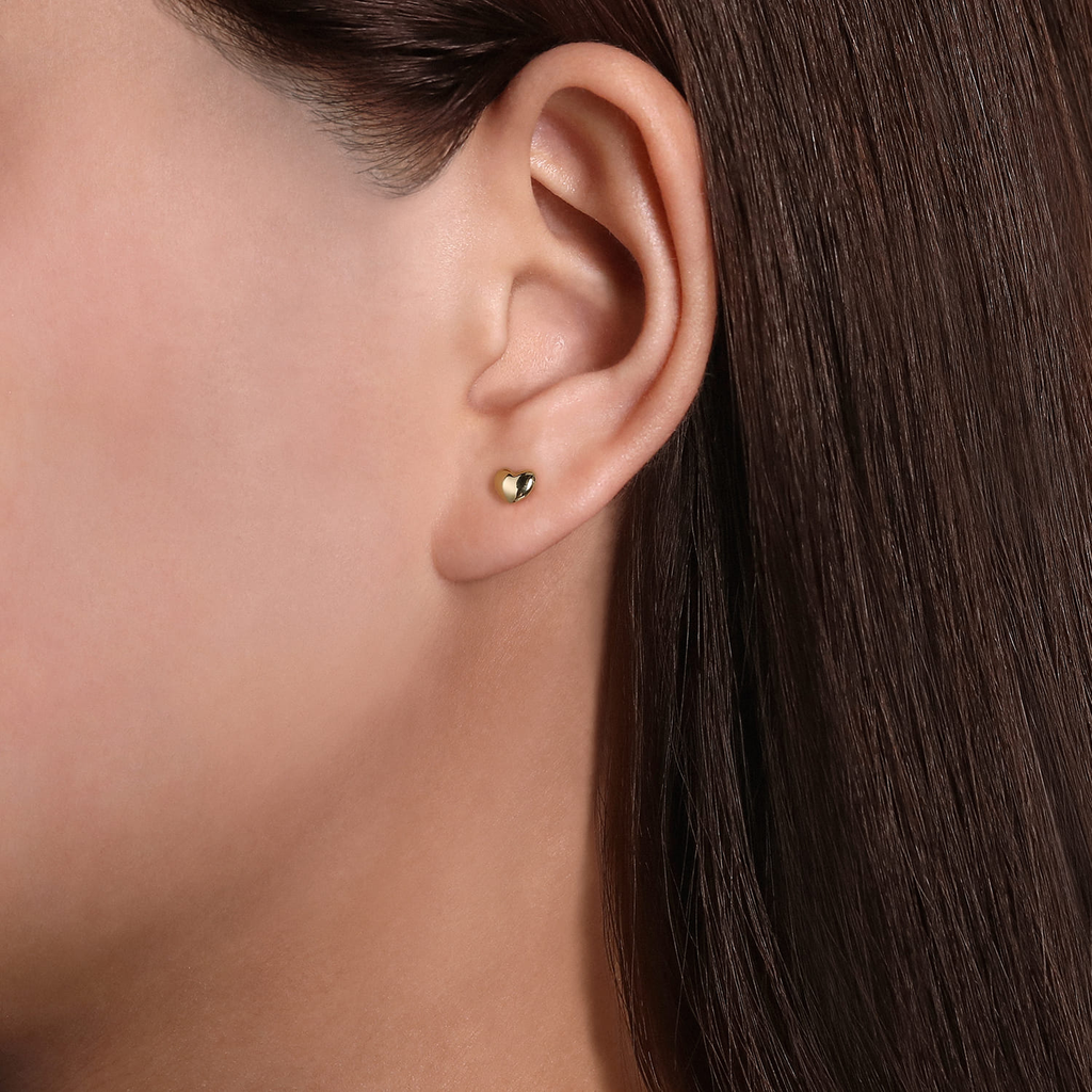 Close-up of an ear wearing a silver stud earring with a clear gemstone.