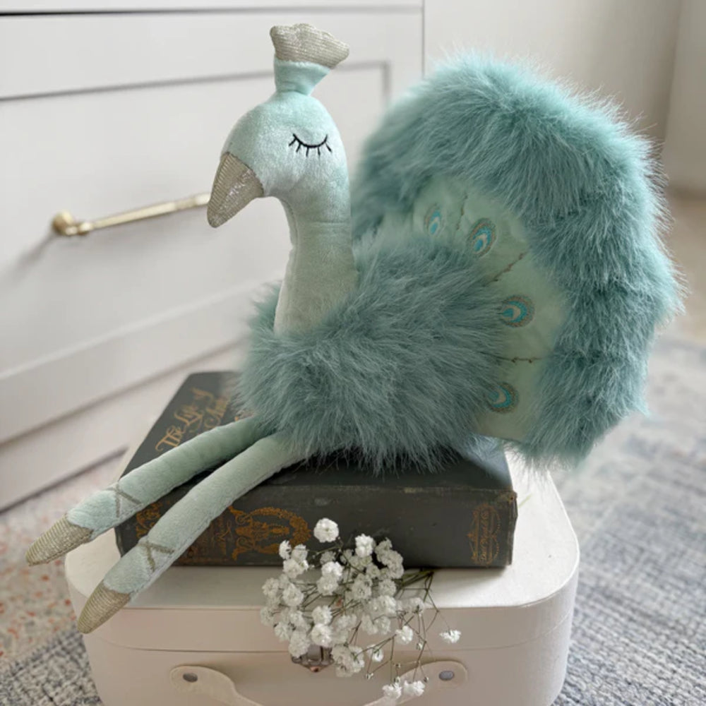 Plush teal blue colored peacock toy on a white stand with a neutral background.