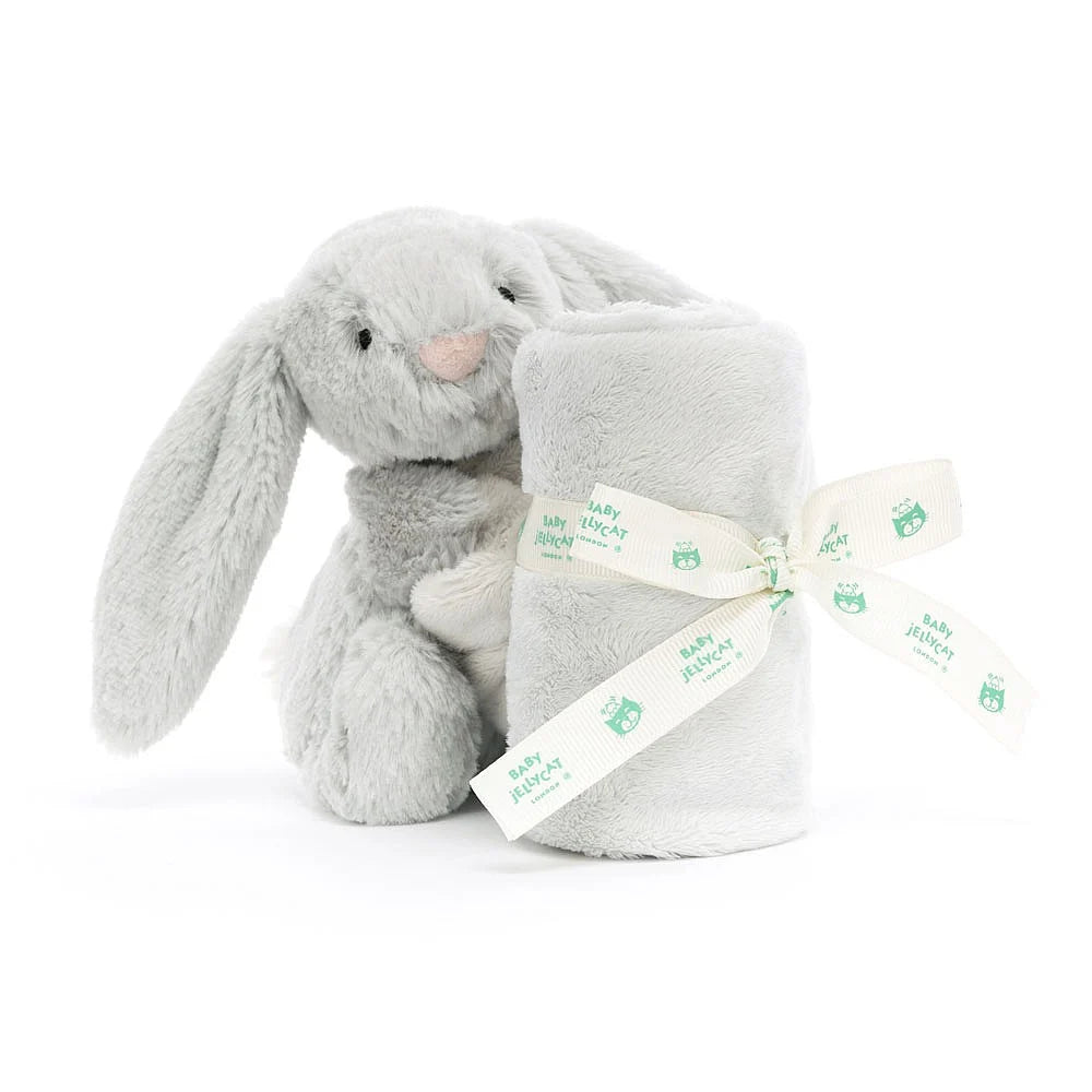Silver grey plush bunny with a rolled grey baby soother blanket on a white backround.