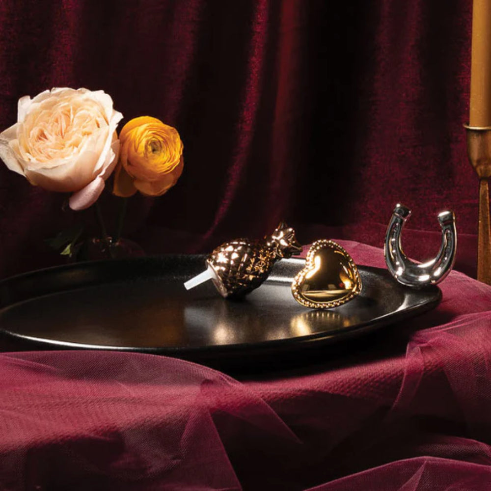 Decorative items on a black plate with flowers against a dark red background.