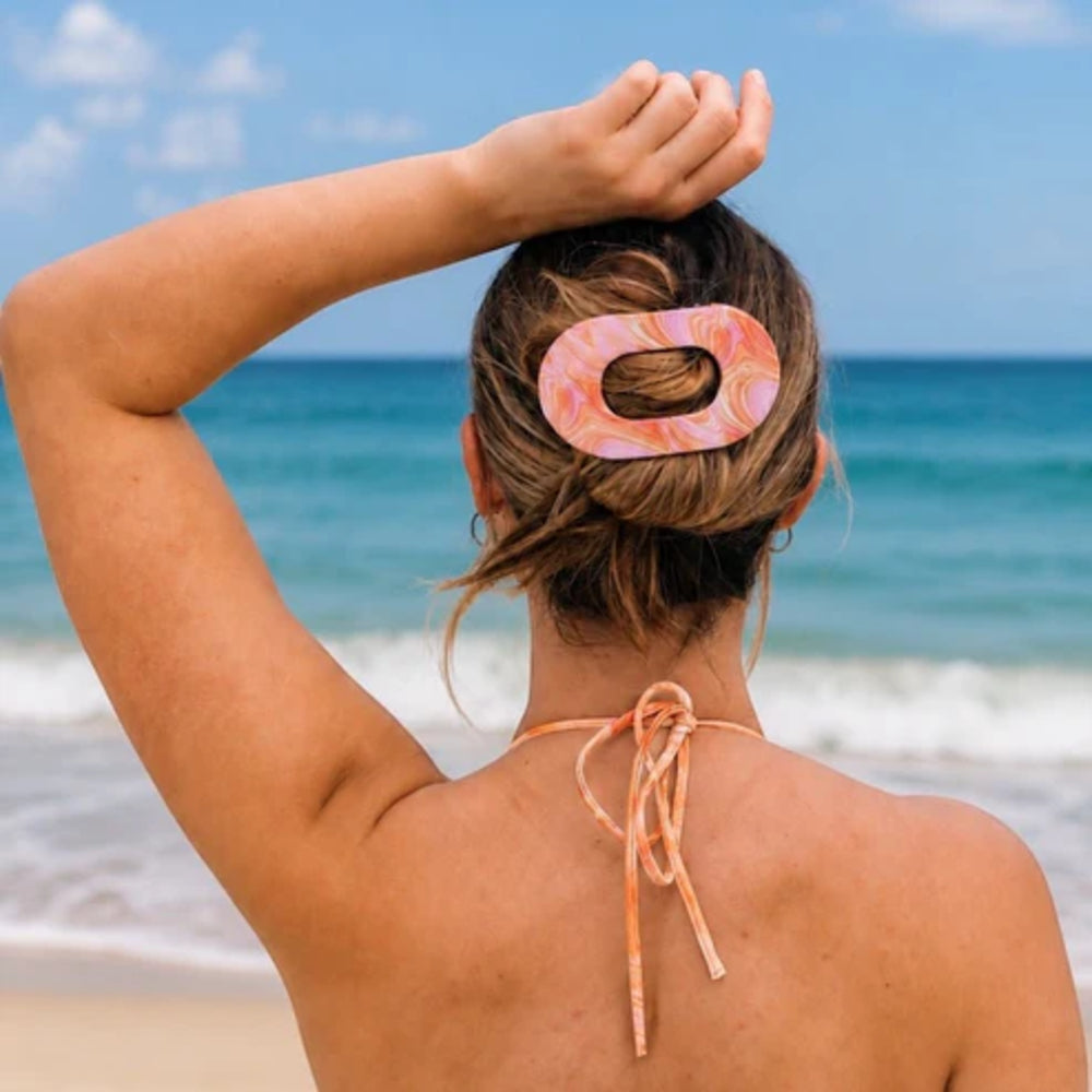 Person with a pink and orange hair clip on a beach